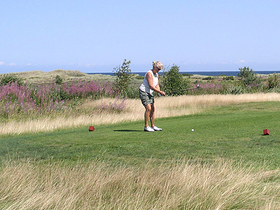Golfspiller med lyng og hav i baggrunden